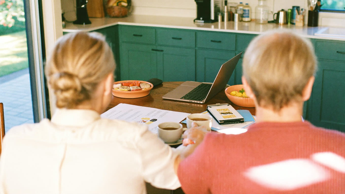 A couple reviewing simple figures together over tea at their kitchen table